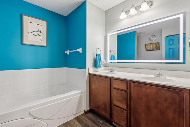 bathroom featuring hardwood / wood-style flooring, vanity, a bath, and a textured ceiling