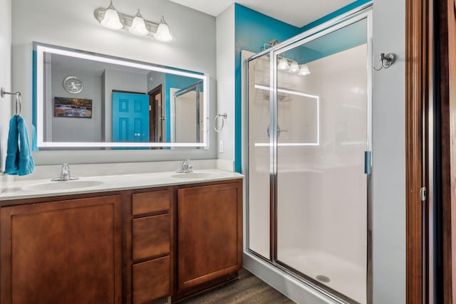 bathroom featuring vanity, a textured ceiling, hardwood / wood-style flooring, and a shower with shower door