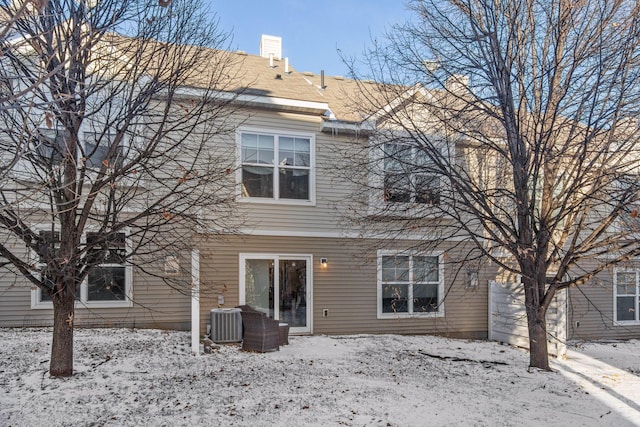 snow covered rear of property featuring central air condition unit