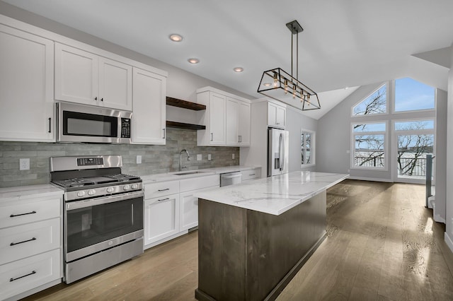 kitchen with hanging light fixtures, light wood-type flooring, appliances with stainless steel finishes, a kitchen island, and white cabinetry