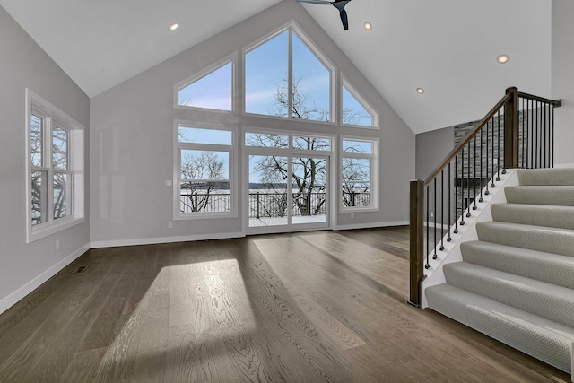 unfurnished living room featuring high vaulted ceiling, ceiling fan, and dark wood-type flooring