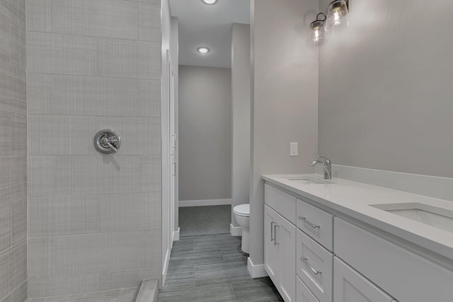 bathroom featuring vanity, toilet, and a tile shower