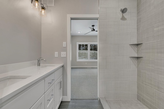 bathroom featuring a tile shower, ceiling fan, and vanity