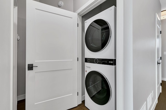 clothes washing area featuring dark hardwood / wood-style floors and stacked washer and dryer