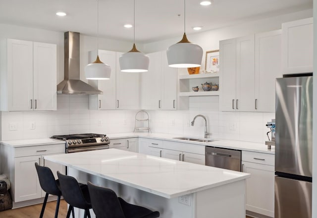 kitchen featuring pendant lighting, white cabinets, sink, wall chimney exhaust hood, and appliances with stainless steel finishes