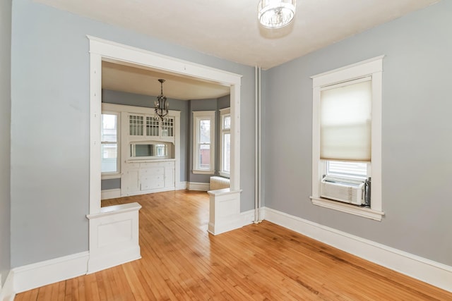 unfurnished dining area with cooling unit, light wood-type flooring, and radiator heating unit