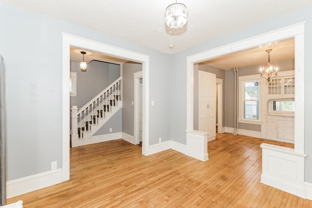 empty room with hardwood / wood-style floors and an inviting chandelier