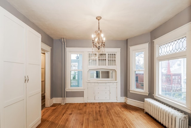 unfurnished dining area with radiator, a healthy amount of sunlight, and light wood-type flooring