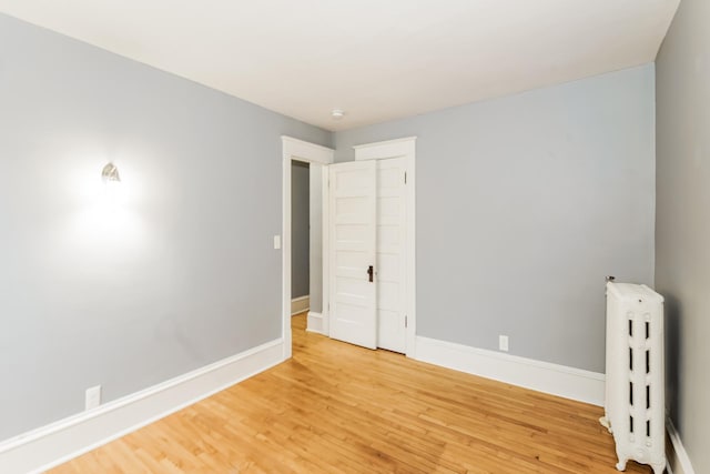 unfurnished room featuring radiator heating unit and wood-type flooring