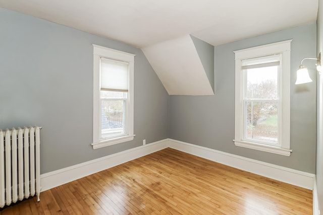 additional living space with hardwood / wood-style flooring, radiator, and vaulted ceiling