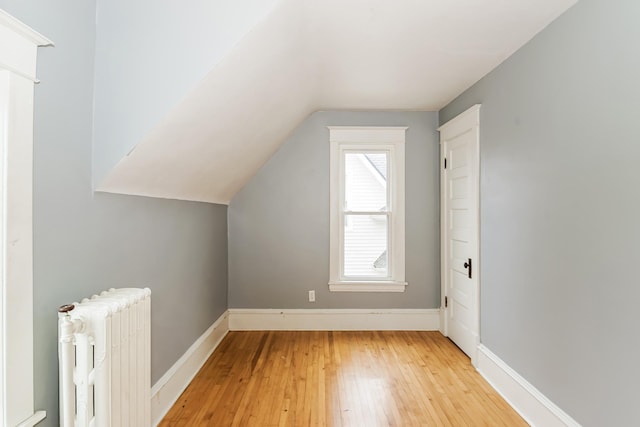 bonus room with radiator, vaulted ceiling, and light wood-type flooring