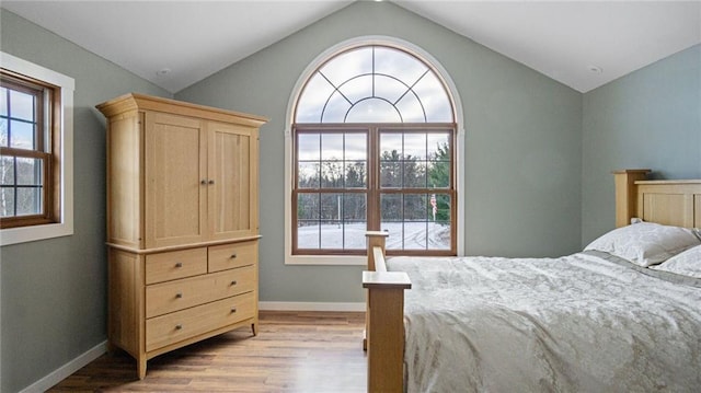 bedroom with light hardwood / wood-style floors and lofted ceiling