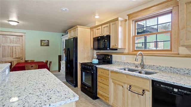 kitchen with light stone countertops, light brown cabinetry, sink, and black appliances