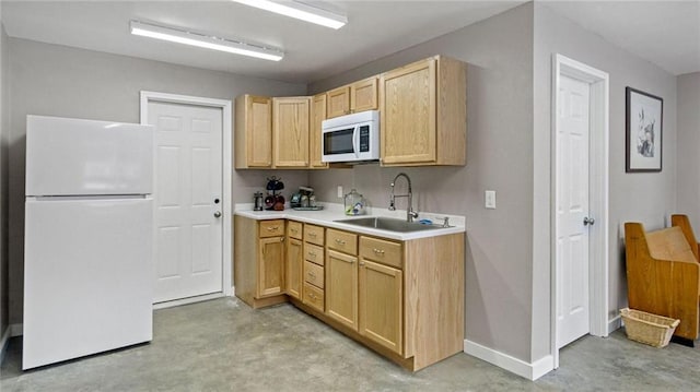 kitchen with light brown cabinetry, white appliances, and sink