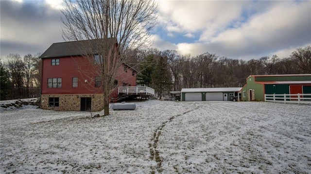 snow covered property featuring a garage and an outdoor structure