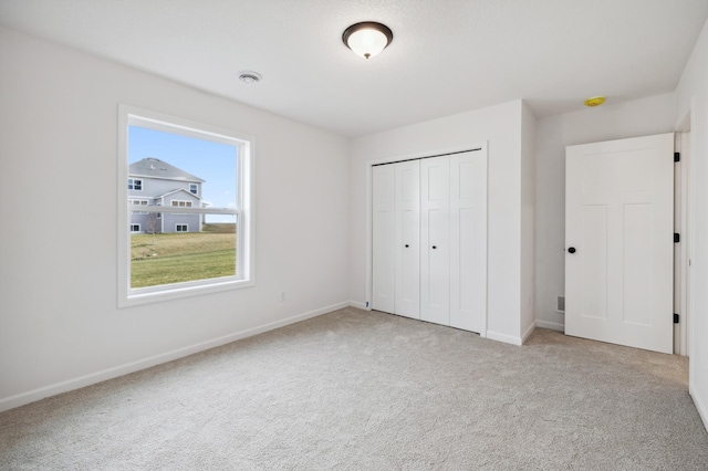 unfurnished bedroom featuring light carpet and a closet