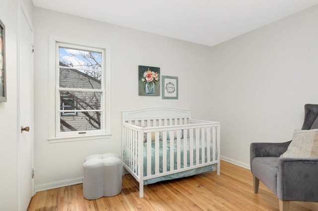 bedroom with hardwood / wood-style flooring and a nursery area