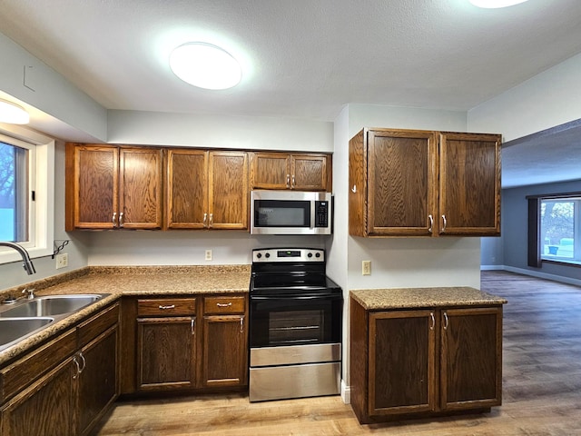 kitchen with sink, light wood-type flooring, a textured ceiling, and appliances with stainless steel finishes