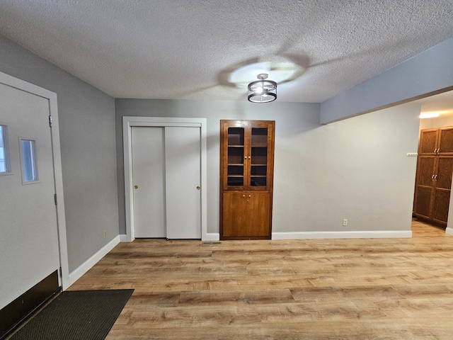 interior space with a textured ceiling and light hardwood / wood-style flooring