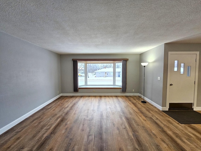 empty room with a textured ceiling and dark hardwood / wood-style flooring