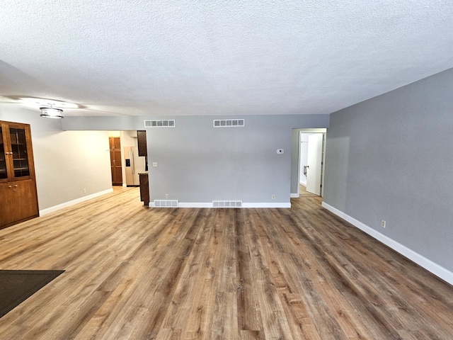 unfurnished living room with wood-type flooring and a textured ceiling