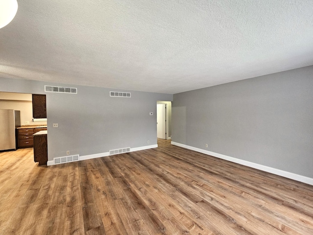 spare room with a textured ceiling and light hardwood / wood-style floors