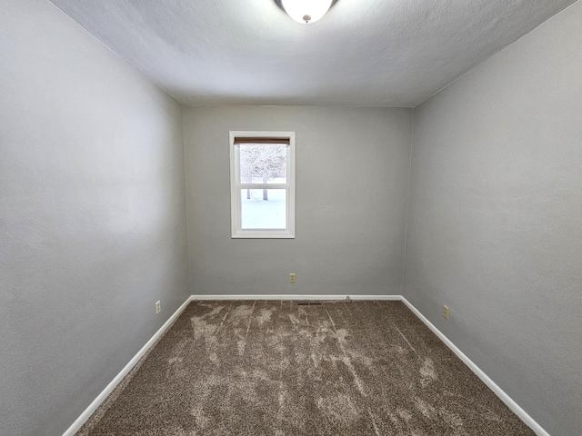 unfurnished room featuring dark colored carpet