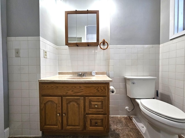 bathroom featuring tile patterned flooring, vanity, toilet, and tile walls