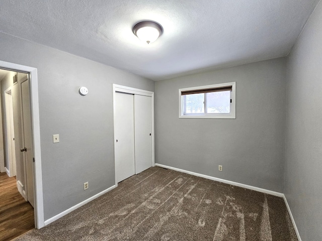 unfurnished bedroom with a closet, dark carpet, and a textured ceiling