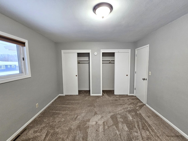 unfurnished bedroom featuring carpet flooring and two closets