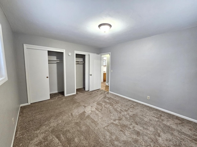 unfurnished bedroom with carpet flooring and two closets