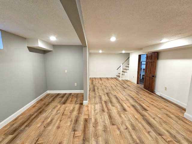 basement featuring a textured ceiling and light hardwood / wood-style flooring