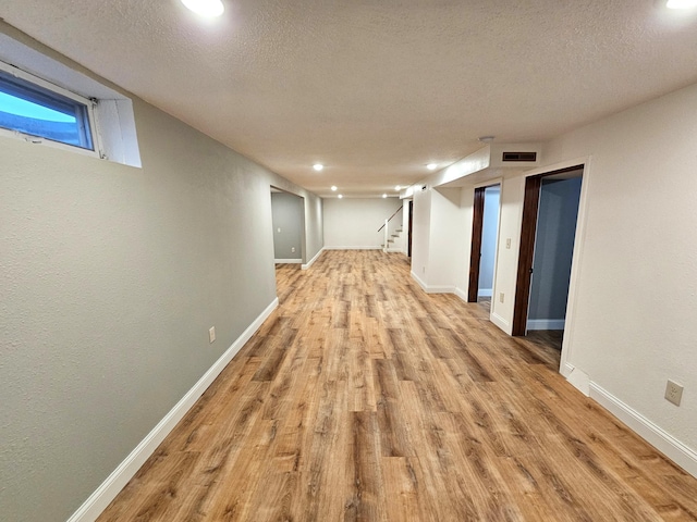 corridor featuring light hardwood / wood-style floors and a textured ceiling