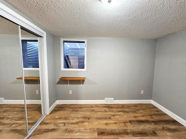 unfurnished bedroom featuring wood-type flooring, a textured ceiling, and a closet