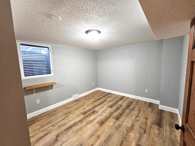 unfurnished room with wood-type flooring and a textured ceiling