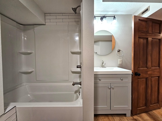 bathroom featuring  shower combination, vanity, wood-type flooring, and a textured ceiling