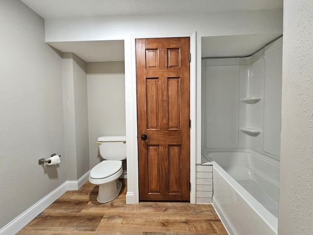 bathroom featuring wood-type flooring, bathtub / shower combination, and toilet