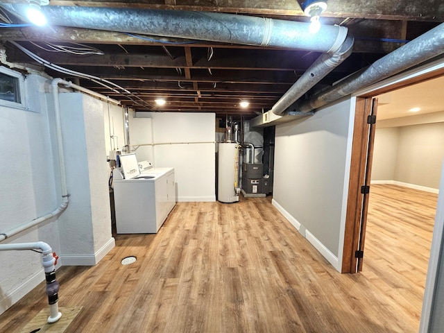 basement featuring heating unit, washing machine and dryer, light wood-type flooring, and water heater