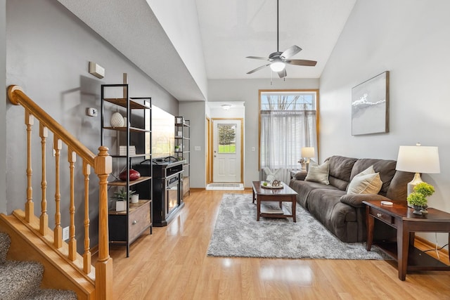 living room with light hardwood / wood-style floors, ceiling fan, and lofted ceiling