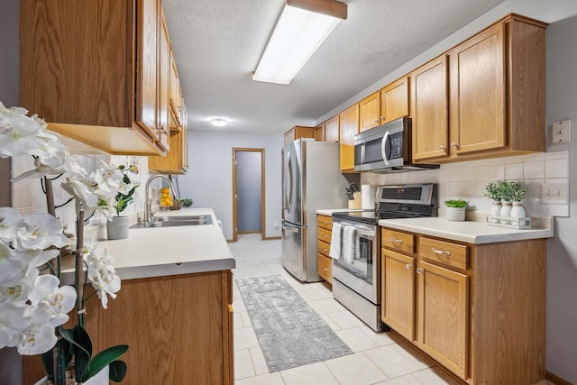 kitchen featuring backsplash, sink, light tile patterned floors, a textured ceiling, and appliances with stainless steel finishes