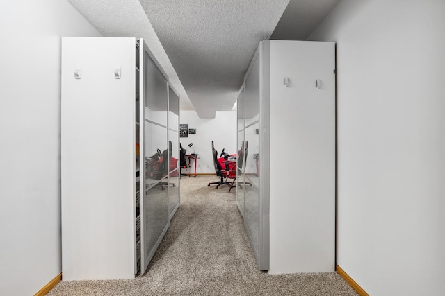 hall featuring a textured ceiling and light colored carpet