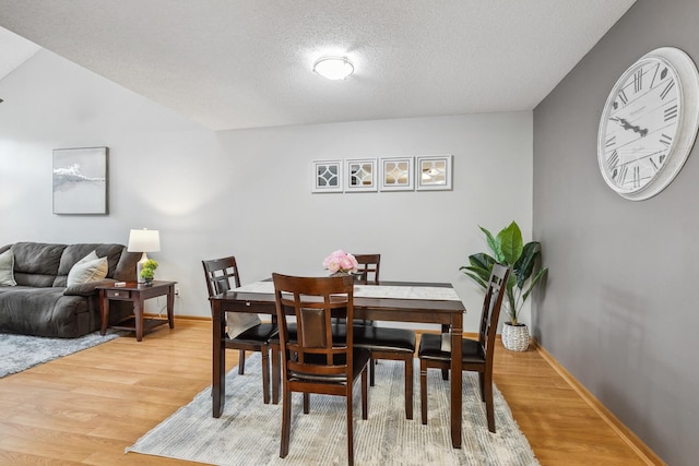 dining area with a textured ceiling, hardwood / wood-style flooring, and lofted ceiling