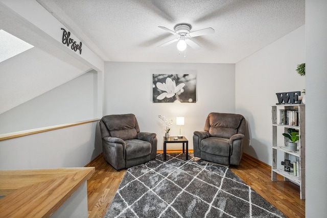 sitting room with a textured ceiling, hardwood / wood-style flooring, ceiling fan, and lofted ceiling