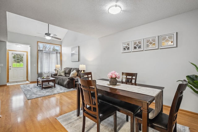 dining space featuring a textured ceiling, ceiling fan, light hardwood / wood-style flooring, and lofted ceiling