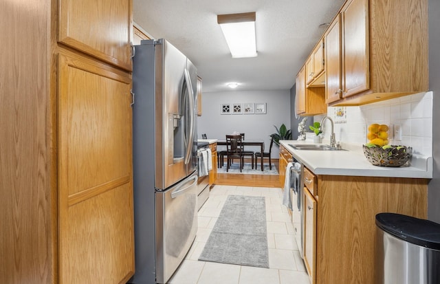 kitchen with backsplash, light tile patterned flooring, sink, and appliances with stainless steel finishes