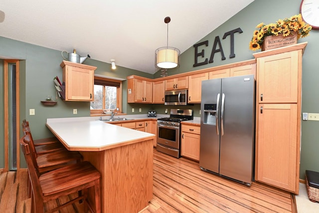 kitchen featuring kitchen peninsula, light brown cabinets, decorative light fixtures, and appliances with stainless steel finishes