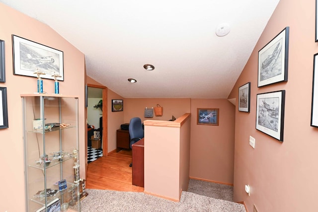 hallway featuring light hardwood / wood-style floors and lofted ceiling