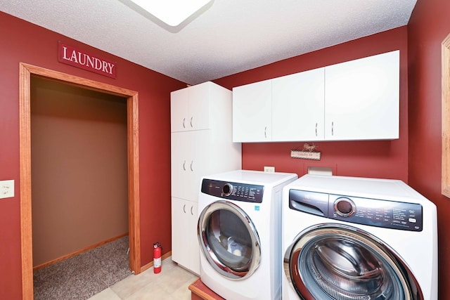 laundry area with cabinets, a textured ceiling, and washing machine and dryer