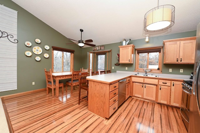 kitchen featuring kitchen peninsula, appliances with stainless steel finishes, vaulted ceiling, and a wealth of natural light