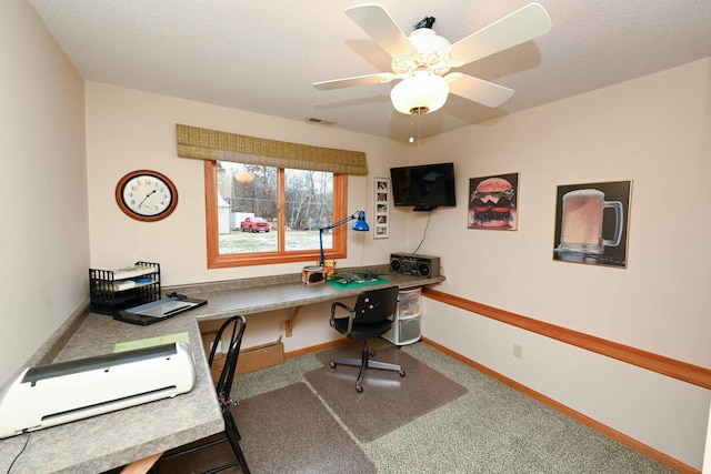 home office with carpet, ceiling fan, built in desk, and a textured ceiling